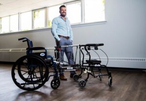 CEO and Founder of Bisep Inc. Daniel Bordenave, standing beside his innovation of a wheelchair being connected to a walker.