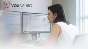 An individual sitting at a desk while looking at reports on a computer monitor.