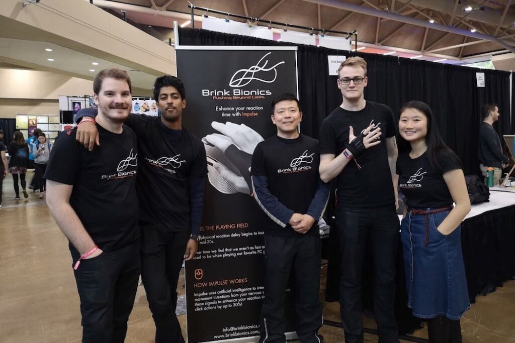 The Brink Bionics team standing in front of their banner at a trade show.