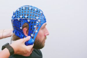 An individual with a silicone cap with sensors on their head