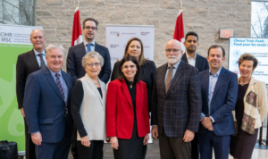 A group photo of seven researchers, standing with McMaster University President David Farrar, MP Filomena Tassi and CIHR President Strong.