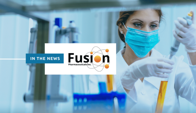 In the news: Fusion Pharmaceuticals. The background image is a woman researcher working in a lab while wearing personal protective equipment (PPE).
