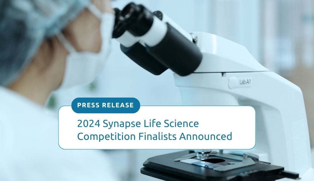 2024 Synapse Life Science Competition Finalists announced. Photo of a researcher wearing a mask and looking down a microscope.