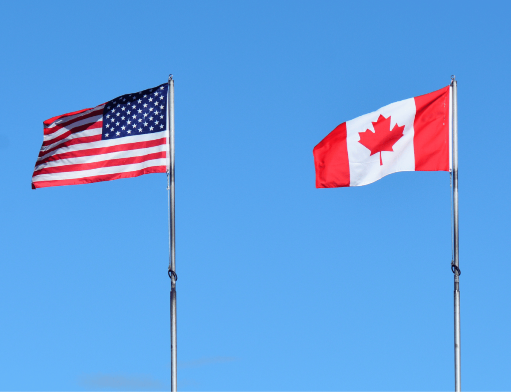 A USA and Canada flag flying in the wind